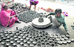 Om Prakash makes diyas ahead of Divali outside his one-room establishment in Jalandhar on Sunday as his wife looks on.
