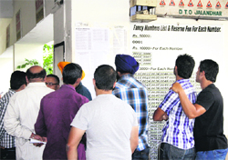 Applicants of fancy numbers check the lists outside the office of District Transport Officer in Jalandhar on Monday. 