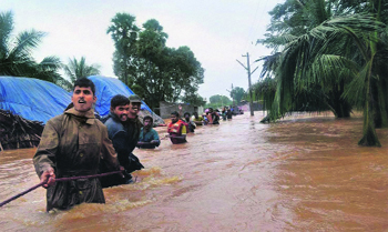 Rescue personnel hold a rope in a flooded area hit by cyclone Nilam in Vizag district.  PTI