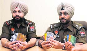 The Additional Deputy Commissioner of Police (Special Branch) shows ATM cards of different banks seized from Pawandeep Singh Bajwa in Jalandhar on Tuesday