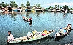 Volunteers collect weeds to clean the Dal Lake in Srinagar on Thursday