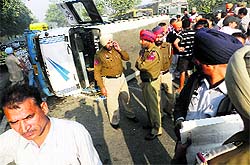 The schoolbus lies overturned on the road near Sahnewal on Thursday
