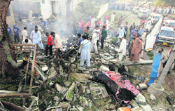Pakistani volunteers and investigators gather at the site of an explosion in Karachi on Thursday.  AP/PTI