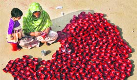 A woman paints dried clay lamps ahead of Divali as her daughter watches, on the outskirts of Jammu.
