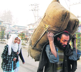 Amid Rising demand: A vendor carries charcoal load in Srinagar on Monday. The demand of coal has increased in the Valley due to the shortage of LPG cylinders.