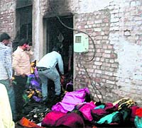 People bring out bundles of clothes from a cloth factory, which was gutted in fire on Divali in Amritsar