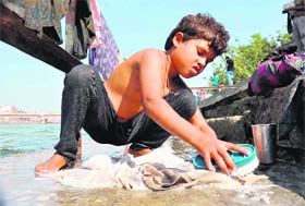 A boy washes clothes on the banks of the Ganga on Childrens Day in Haridwar on Wednesday