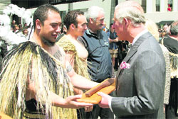 Britain's Prince Charles receives a gift from a Maori warrior as a Maori whaka canoe is launched during a walkabout on the waterfront in Wellington on Wednesday