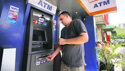 American tourist Ryan Russell withdraws cash from an ATM using a MasterCard card, the first such ATM transaction, in Yangon (Rangoon) on Thursday. MasterCard Inc had announced in September that it had reached an agreement with a bank in Myanmar to issue its first branded cards in the country, which, emerging from isolation after years of military rule, has an antiquated banking system and a largely cash economy. 