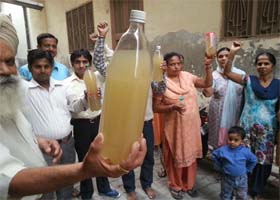 Residents of the Mehna Chowk area show the dirty water that is being supplied to them