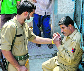 A policeman lights a cigarette of his colleague at a public place in Srinagar.