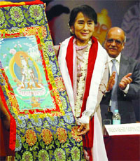 Myanmar opposition leader and National League for Democracy Chairperson Aung San Suu Kyi poses with a Thangka painting presented to her during her visit to Lady Sri Ram College, while the Chairman of the college, Arun Bharat Ram, looks on in New Delhi on Friday