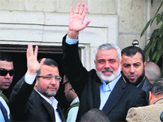 Gazas Hamas Prime Minister Ismail Haniyeh (right) and Egyptian Prime Minister Hesham Kandil wave to the crowd as they meet in Gaza City on Friday.