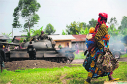 A displaced Congolese woman walks past a retreating army tank in a village near Goma, following an alleged ambush by M23 rebels in the Democratic Republic of the Congos restive North Kivu province.