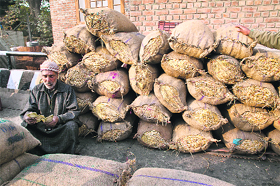 A charcoal seller counts money near the stock on a road in Srinagar. 