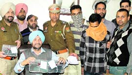 CIA officials show the pistols and drugs seized from the two youths (with covered faces) in Jalandhar on Sunday.