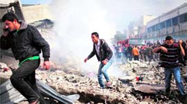 Palestinians run for cover after an Israeli air strike on a house in Gaza City on Sunday.