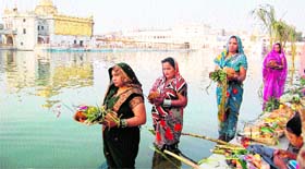 Women offer prayers to the sun on the occasion of Chhat Puja at Durgiana Temple in Amritsar on Monday.