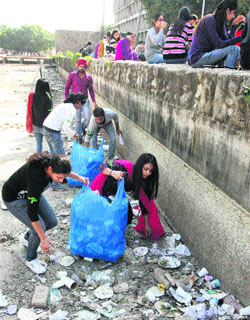 Students of the PU and workers of an NGO clean a pond in the PU on Monday. 