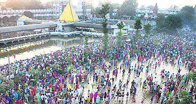 Hundreds of migrants from Uttar Pradesh and Bihar stand in the holy pond of Devi Talab Mandir to offer prayers during Chhat Puja in Jalandhar on Monday. 