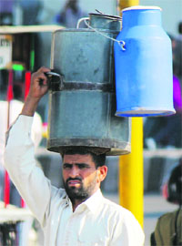 A man carries cans of milk in Jammu. 