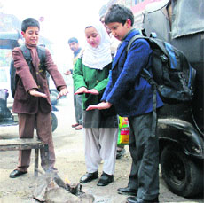 Schoolchildren gather around a fire to keep themselves warm in Srinagar on Monday. 