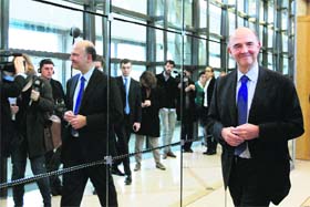 French Finance Minister Pierre Moscovici (R) leaves after a news conference at the Economy Ministry in Paris on Tuesday