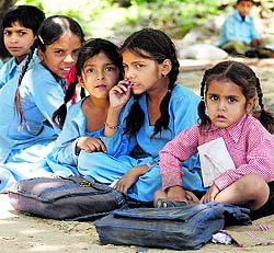 Children sit under the open sky at a school on the outskirts of Jammu