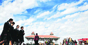 People walk amid cloudy weather at the Ridge in Shimla on Thursday