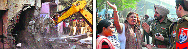 A JCB machine pulls down the front wall of a house in Chhawni Mohalla during a demolition drive of the MC in Ludhiana on Thursday; and (right) a woman argues with police officials against the drive.