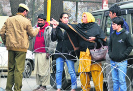 A policeman stops people near a barbed fence in Srinagar on Friday. The authorities imposed prohibitory orders in various areas to thwart Muharram procession.