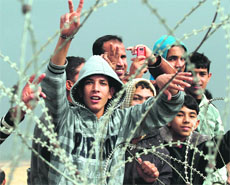 Palestinian youths gesture during a demonstration next to the security fence on the Gaza border with Israel. 