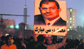 A protester holds up a poster with the faces of Egyptian ex-President Hosni Mubarak and President Mohamed Morsi at Tahrir Square.