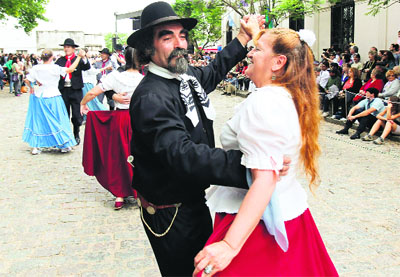 Couples, wearing traditional outfits, dance to folk music during Tradition Day celebrations in San Antonio de Areco, near Buenos Aires.