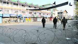 Security personnel patrol a deserted street at Lal Chowk in Srinagar on Sunday. The district administration has imposed restrictions in the city to thwart Muharram processions