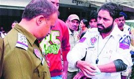 Traffic policeman Sardara Singh shows his injured wrist to a policeman in Amritsar. 