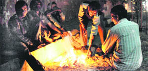 People sit by a bonfire to warm themselves on a cold night in Amritsar on Monday.