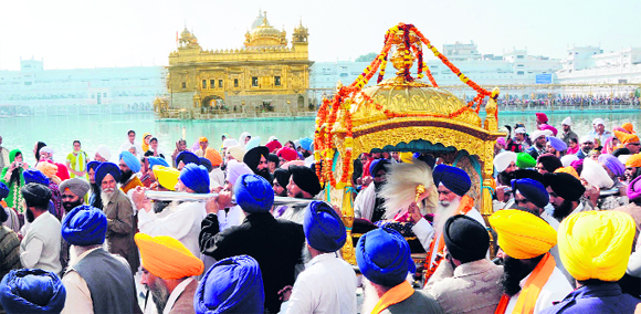 Sikh devotees carry the palanquin during a procession at the Golden Temple in Amritsar on Tuesday, the eve of the birth anniversary of Sri Guru Nanak Dev. 