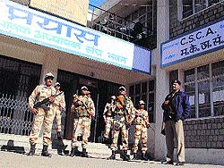 Security personnel guard electronic voting machines kept in a strong room at Dharamsala on Wednesday