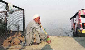 Little indulgences: A boatman enjoys a hukkah on the banks of the Dal Lake in Srinagar on Wednesday