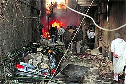 Syrian men inspect the scene of a car bomb explosion in Jaramana
