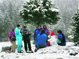 Tourists enjoy fresh snowfall near Kothi, 12 km from Manali, on Thursday.