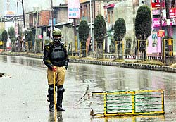 A policeman stands guard at a barricade set up in Srinagar on Thursday