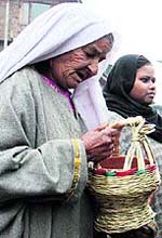 An elderly woman looks at kangri, a traditional firepot, in Srinagar on Thursday