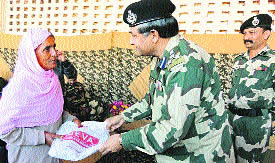 A BSF officer presents a token gift to a woman during the 47th Raising Day celebrations in Rajouri on Friday. 