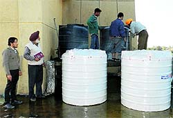 MC officials replacing the damaged water tanks at the MC's Zone D building in Ludhiana on Friday