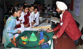  participants explain their models to the visiting students at the exhibition.