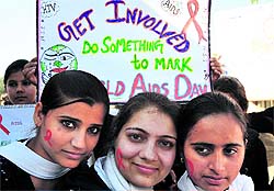Volunteers of NSS paint their cheeks with red ribbon symbol to mark World AIDS Day in Jammu on Saturday