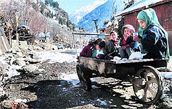 Children on a hand-cart surrounded by snow-clad mountains in a remote village near Pahalgam on Saturday