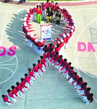 Students form a red ribbon (symbol of AIDS) on the occasion of World AIDS Day at a school in Patiala on Saturday